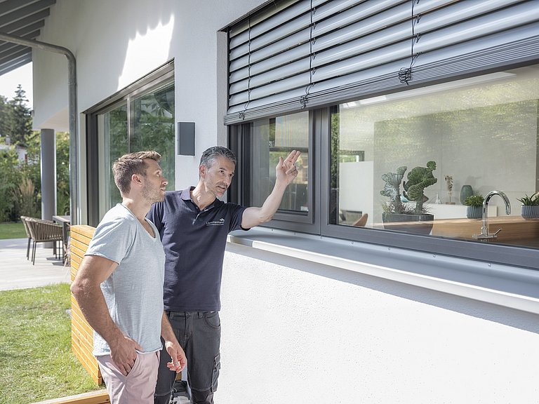 Fachberater von Lämmermann zeigt einem Kunden das Fliegengitter am Fenster